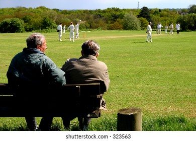 A Couple Of Elderly Citizens Watching A Village Cricket Match