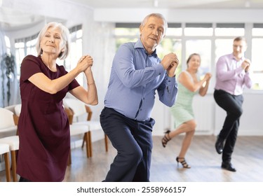 Couple of elderly man and elderly woman dancing twist in studio - Powered by Shutterstock