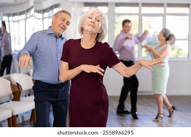 Couple of elderly man and elderly woman dancing twist in studio - Powered by Shutterstock