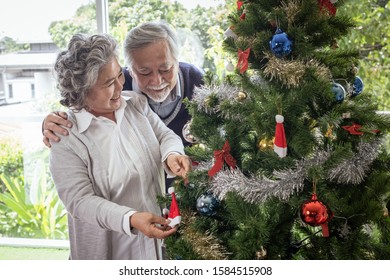 Couple of elderly man and woman happy with smile and help to prepare and gift or decorate Christmas tree in living room that decorated for christmas festival holiday concept - Powered by Shutterstock