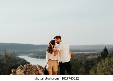 Couple Embracing And Kissing On The Hill With Incredible Landscape. Emotional Date, Hugs And Kisses During Sunny Day.