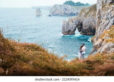 Couple embracing themselves while looking at the sea