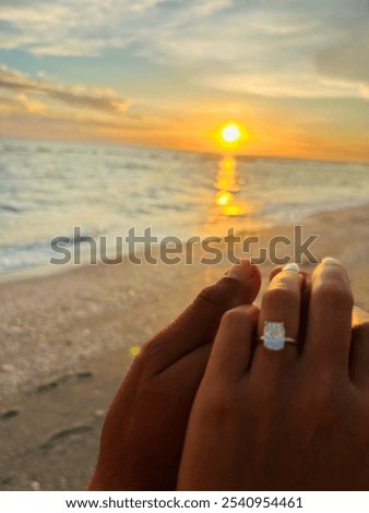 Couple engaged on beach holding hands at sunset 