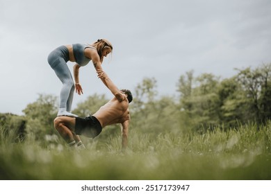 A couple engages in acrobatic yoga in a park, demonstrating balance, strength, and teamwork in an outdoor setting. - Powered by Shutterstock