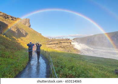 A couple enjoying the amazing Gullfoss waterfall with rainbow, Iceland - Powered by Shutterstock