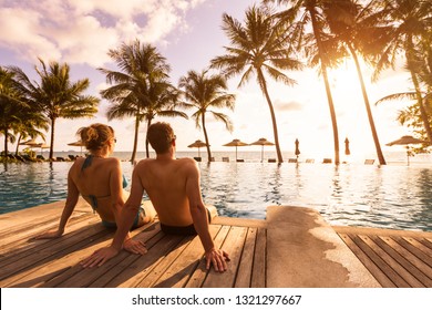 Couple Enjoying Beach Vacation Holidays At Tropical Resort With Swimming Pool And Coconut Palm Trees Near The Coast With Beautiful Landscape At Sunset, Honeymoon Destination