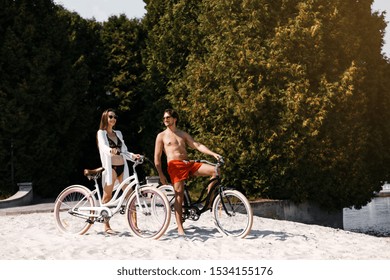 A Couple Enjoying A Day At The Beach Riding A Tandem Bike.