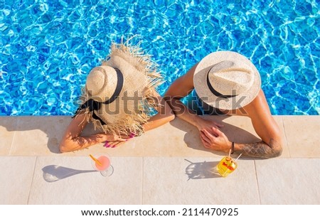 Couple enjoying drinks by the pool, overhead view