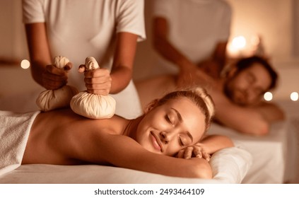 Couple Enjoying Herbal Massage. Relaxed Husband And Wife At Exotic Spa Resort, Lying With Eyes Closed Receiving Thai Massage With Aromatic Bags. Body Beauty Treatment, Relaxation And Wellness - Powered by Shutterstock