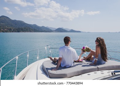 Couple Enjoying Honeymoon Onboard Of Luxury Boat, Luxurious Yacht In Tropical Sea, Man And Woman Drinking Coconuts And Relax