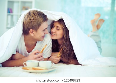 Couple enjoying one another while having breakfast in bed - Powered by Shutterstock