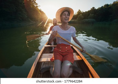 Couple enjoying a ride on a canoe. Smiling couple paddling boat on the sunset lake