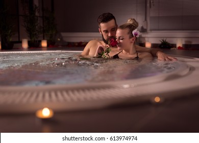 Couple enjoying in a romantic atmosphere of a luxury spa wellness resort, having a bath in a jacuzzi tub