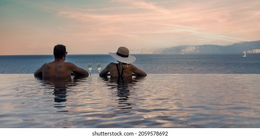 couple enjoying romantic view to the sea and drinking champagne in infinity pool at luxury resort. banner copy space - Powered by Shutterstock