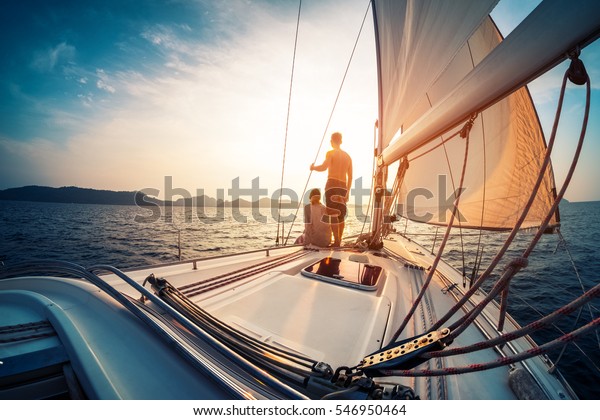Couple enjoying sunset from the deck of the sailing\
boat moving in a sea