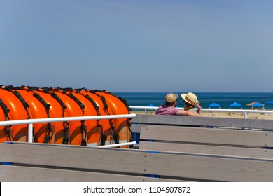 A Couple Enjoying A View Over The Ocean 
 And A Sandy Beach Resort From A Passenger Ferry. Summer In New England.