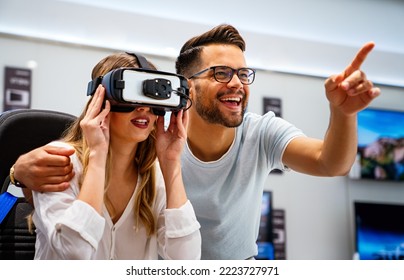 Couple Enjoying With VR Goggles At Tech Store. Shopping Virtual Reality People Concept