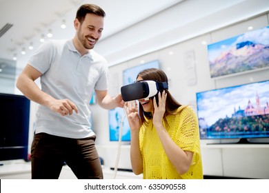 Couple enjoying with VR goggles at tech store. Shopping couple having fun at marketplace.