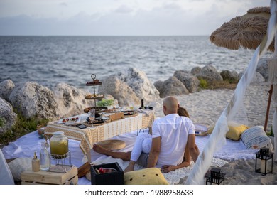 A Couple Enjoys A Luxury Picnic On The Beach With A Scenic Ocean View