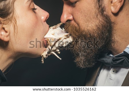 Couple enjoys meal, meat or fowl. Man and woman with chickens skeleton in mouths on black background. Couple eats chicken together. Enjoy your meal concept. Weird aesthetics, closeness and intimacy.