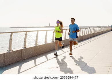 Couple enjoys morning run along seaside promenade with sunlight reflecting on water - Powered by Shutterstock