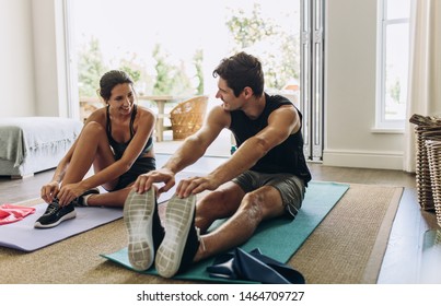 Couple exercising together. Man and woman in sports wear doing workout at home.