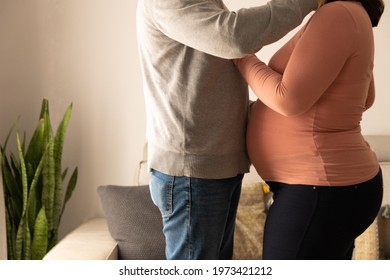 Couple expecting a baby in an affectionate attitude in their home, at the living room - Powered by Shutterstock