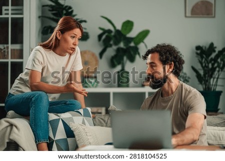 Couple facing relationship problems at home. Woman expressing disagreement and frustration as man is preoccupied with a laptop