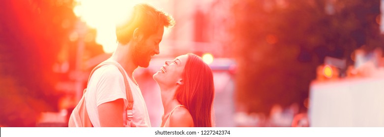 Couple falling in love dating laughing having fun on summer outdoor date in sunset. Panorama banner. Interracial young couple attracted looking into each other's eyes. Asian girl, Caucasian man, 20s.