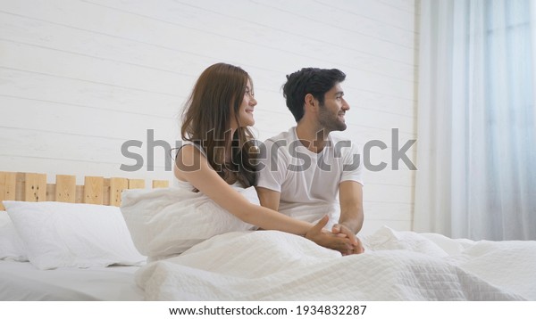 A couple family.\
Middle east young man and Asian woman waking up, sleeping together.\
People lying on bed in bedroom in early morning at home. Lifestyle.\
Love. Multi ethnic
