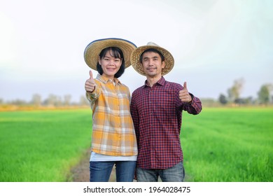 Couple farmers man and woman standing and thumb up at green rice farm. - Powered by Shutterstock