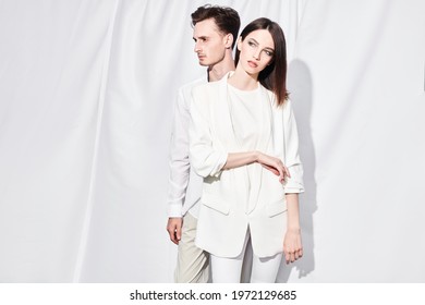 Couple Of Fashionable Young People Posing Outdoor In White Clothes Against A White Fabric Background. Summer Style. Fashion.