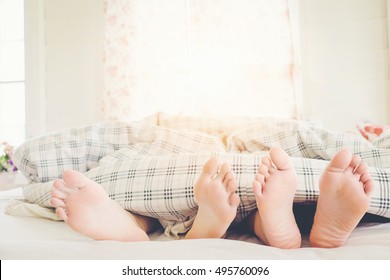 Couple Feet Sleeping In Bed