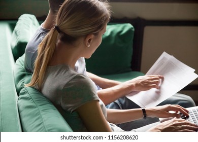 Couple filling online form on website or using laptop application checking information with papers, calculating domestic bills, considering document contract terms analyzing bank loan conditions - Powered by Shutterstock