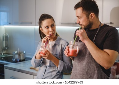 Couple flirting in the kitchen while drinking smoothie with a straw - Powered by Shutterstock