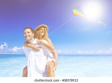 Couple Flying A Kite On The Beach.