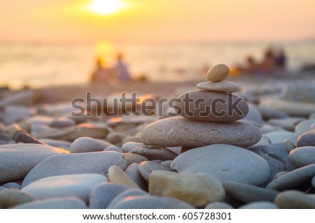 a couple and folded pyramid Zen pebble stones on the sea beach at sunset
