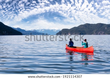 Couple friends canoeing on a wooden canoe during a sunny day. Colorful Sky Art Render. Taken in Harrison Lake, East of Vancouver, British Columbia, Canada.