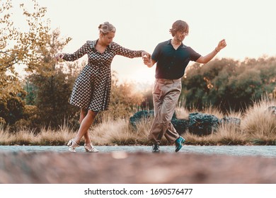 Couple of friends dancing swing in the sunset at the park. Couple of young people having fun dancing lindy hop Lifestyle concept.