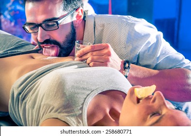 Couple Of Friends Having Fun In Disco Night Club With Body Tequila Drink Party - Nightlife With Crazy Game For Young People - Vintage Look With Soft Focus On Glass And Salt With Shallow Depth Of Field