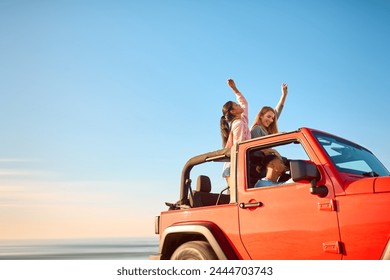 Couple With Friends On Vacation Driving Car On Road Trip Adventure To Beach Standing Up Through Roof - Powered by Shutterstock