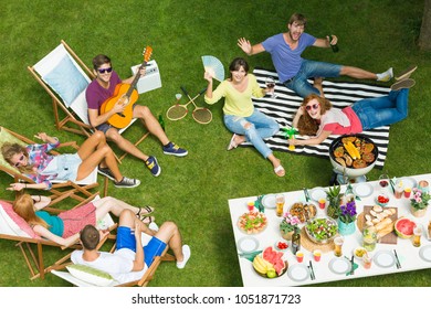 Couple Of Friends Relaxing At The Barbeque Party Listening To The Guitar