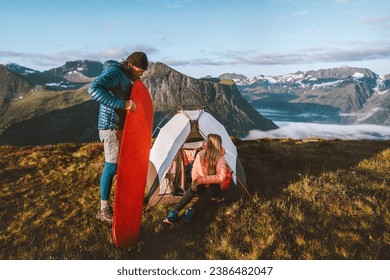 Couple friends setting up tent camping gear travel in mountains, man inflating sleeping pad, active vacations outdoor adventures man and woman hiking together family tour healthy lifestyle in Norway - Powered by Shutterstock