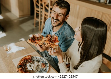 A couple of friends shares a moment over a rustic table, savoring a perfectly baked pizza topped with fresh ingredients and accompanied by a glass of wine. - Powered by Shutterstock