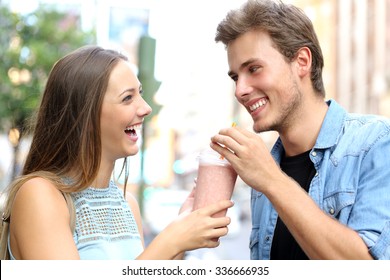 Couple or friends sharing a milkshake and laughing in the street - Powered by Shutterstock