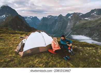 Couple friends traveling together with camping tent gear romantic vacations man and woman hiking adventure outdoor family healthy lifestyle explore mountains of Norway - Powered by Shutterstock