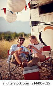 Couple In Front Of Camper Rv Having Small Talk And Laughing. Roadtrip Summer Holiday. Fun, Togetherness, Travel, Nature Concept.