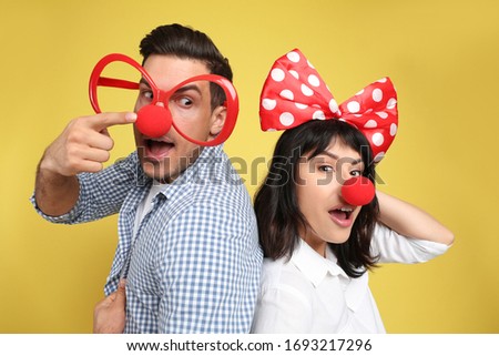 Couple with funny accessories on yellow background. April fool's day
