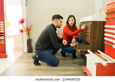 Couple At The Furniture Store. Handsome Man And Beautiful Woman Buying A Bathroom Cabinet For Their New Home 