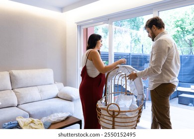 Couple of future parents with pregnant woman preparing the crib of the future baby with copy space - Powered by Shutterstock